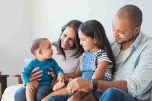Família sorrindo em casa com pais e dois filhos, ilustrando o reagrupamento familiar em Portugal.
