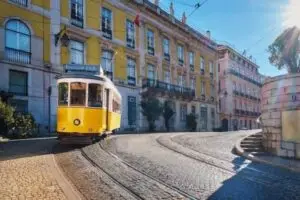 Bondinho amarelo tradicional em uma rua de paralelepípedos em Lisboa, Portugal, ilustrando o Visto D2 para empreendedores.